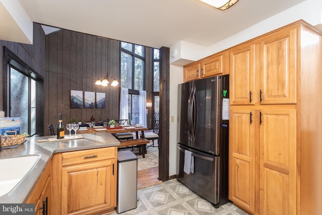 kitchen with stainless steel fridge, light wood-type flooring, sink, pendant lighting, and a chandelier