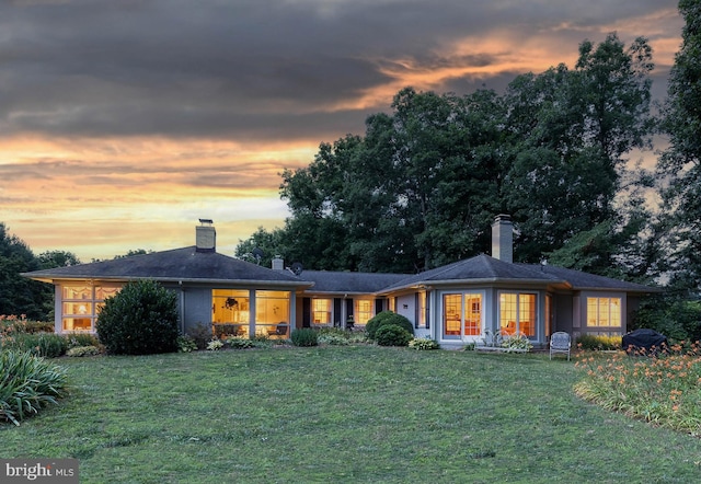 back house at dusk with a lawn