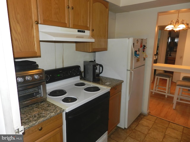 kitchen with electric stove, white fridge, pendant lighting, light stone counters, and a chandelier