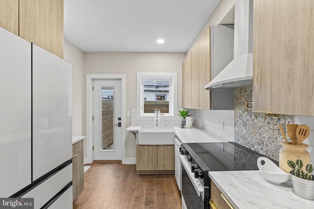 kitchen with wall chimney range hood, tasteful backsplash, dark hardwood / wood-style flooring, range with electric cooktop, and sink