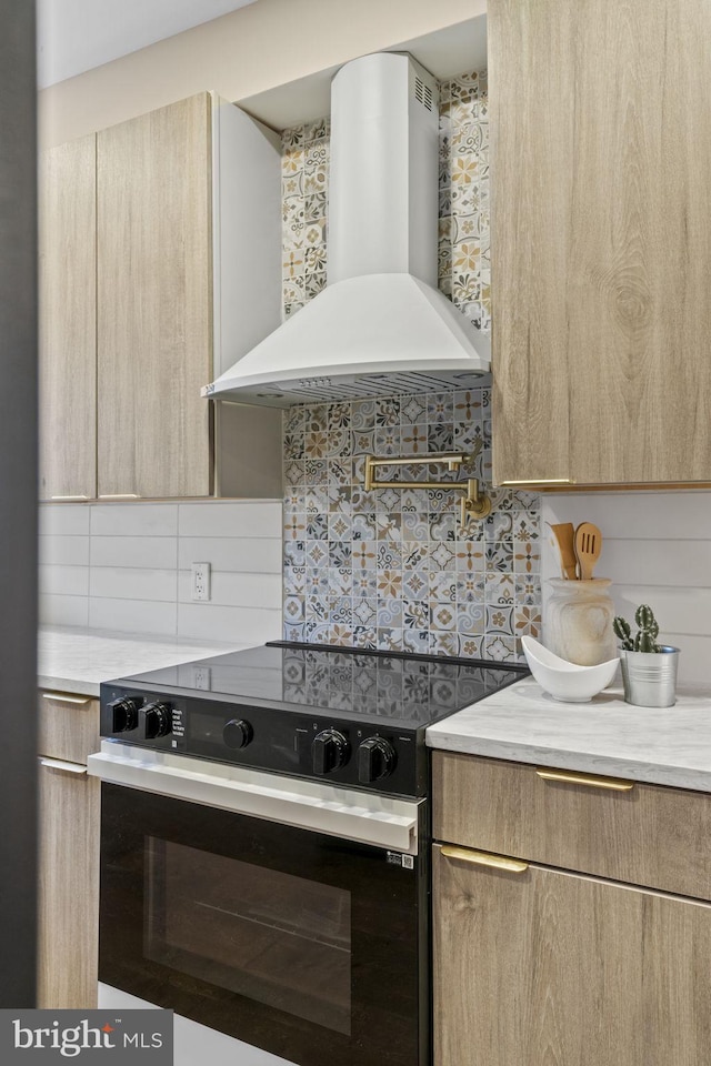 kitchen featuring black range with electric stovetop, decorative backsplash, wall chimney exhaust hood, and light brown cabinets