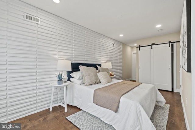 bedroom with a barn door and dark hardwood / wood-style flooring