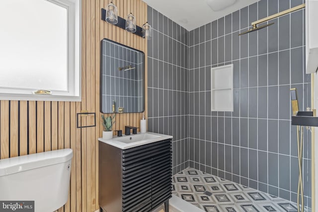 bathroom featuring toilet, tiled shower, and vanity