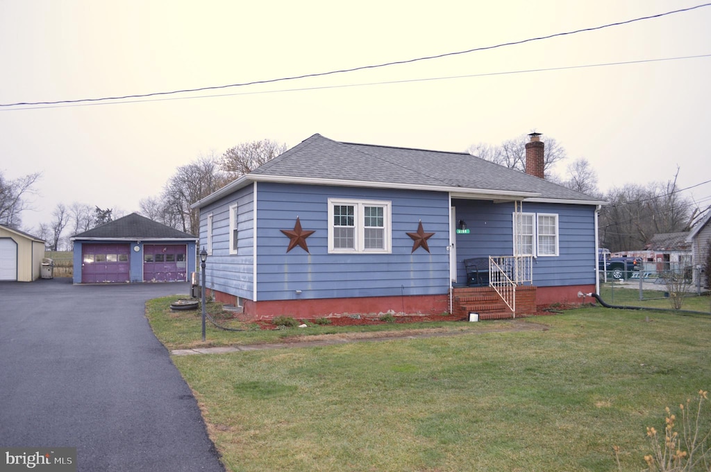 view of front facade featuring a garage, an outbuilding, and a front lawn