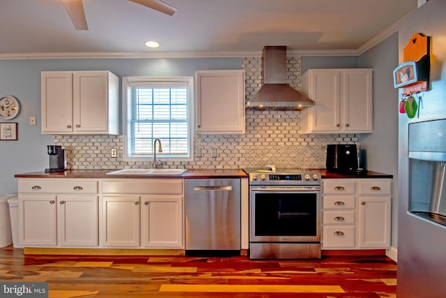 kitchen featuring white cabinetry, stainless steel appliances, decorative backsplash, wall chimney range hood, and sink