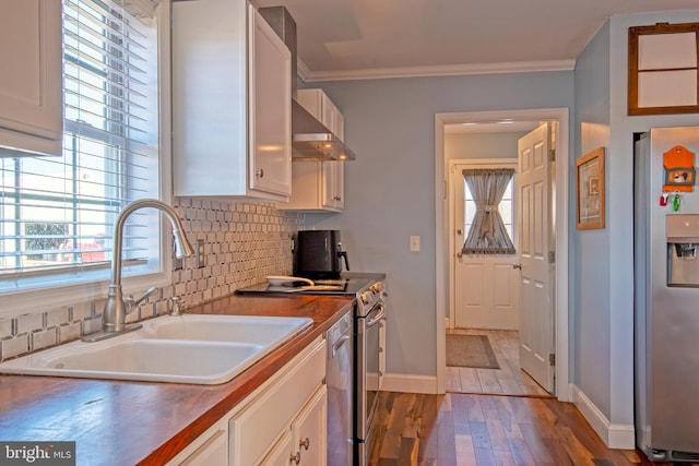 kitchen featuring stainless steel appliances, wall chimney exhaust hood, white cabinets, and sink