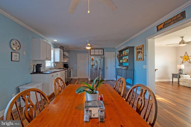 dining space with ceiling fan, ornamental molding, light hardwood / wood-style floors, and sink