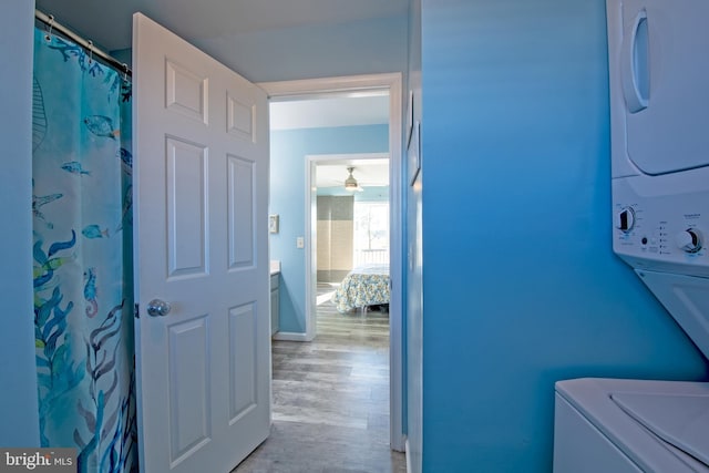 washroom with stacked washer / dryer and light hardwood / wood-style flooring