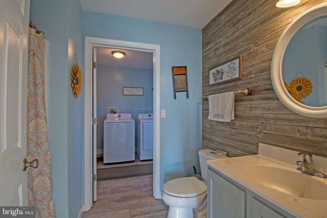 bathroom featuring vanity, toilet, washing machine and clothes dryer, and wooden walls