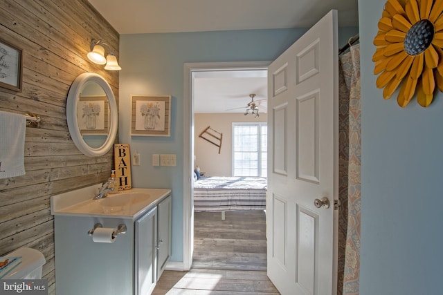 bathroom featuring hardwood / wood-style flooring, ceiling fan, wood walls, and vanity