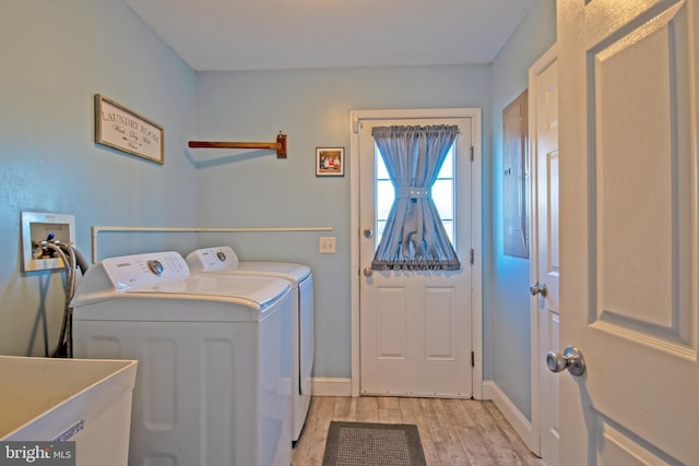 clothes washing area with light wood-type flooring, separate washer and dryer, and sink