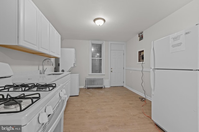 kitchen with white appliances, sink, radiator heating unit, light wood-type flooring, and white cabinetry