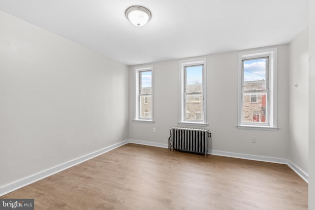 spare room featuring light wood-type flooring and radiator heating unit