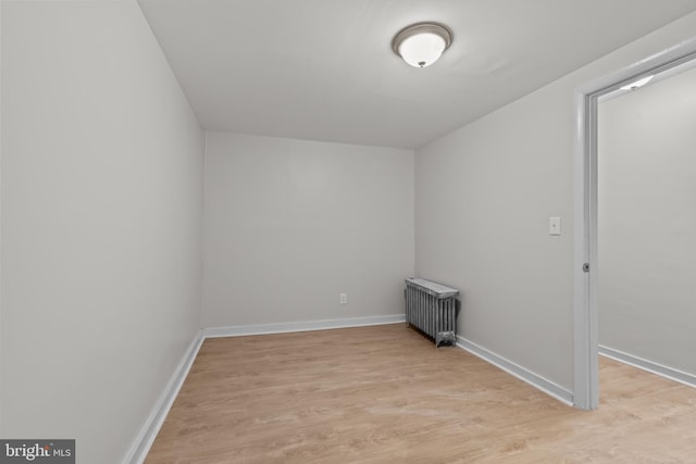 unfurnished room featuring radiator heating unit and light hardwood / wood-style flooring