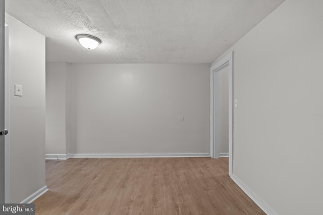 spare room with light wood-type flooring and a textured ceiling