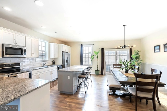 kitchen with a center island, hanging light fixtures, a breakfast bar, white cabinets, and appliances with stainless steel finishes