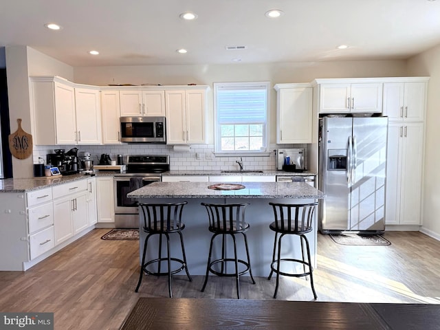 kitchen featuring light stone countertops, appliances with stainless steel finishes, light wood-type flooring, and white cabinetry