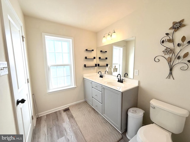 bathroom with wood-type flooring, vanity, toilet, and plenty of natural light