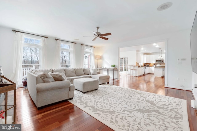 living room featuring ceiling fan, wood-type flooring, and a wealth of natural light