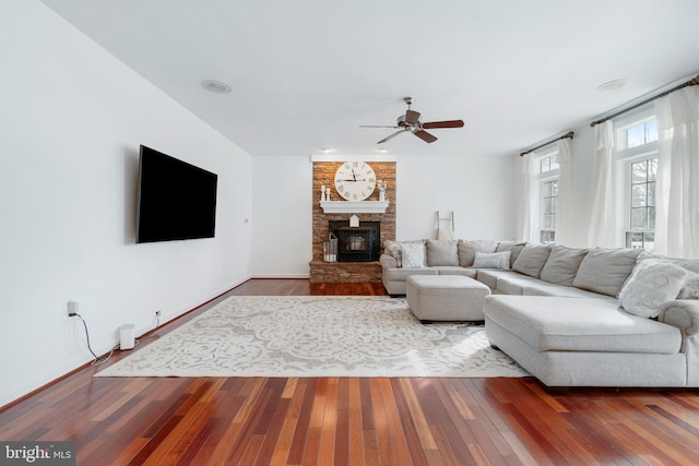 living room featuring hardwood / wood-style floors, a wood stove, and ceiling fan