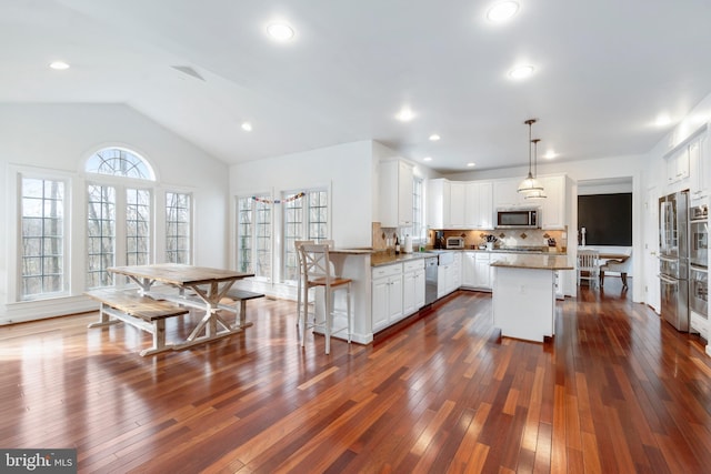 kitchen featuring tasteful backsplash, stone countertops, a breakfast bar, white cabinets, and appliances with stainless steel finishes