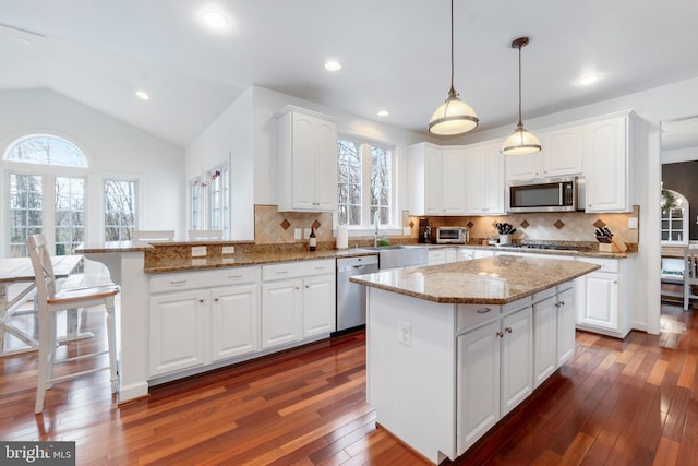 kitchen with white cabinets, pendant lighting, lofted ceiling, and stainless steel appliances