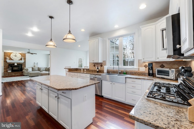 kitchen with hanging light fixtures, stainless steel appliances, a kitchen island, and white cabinetry