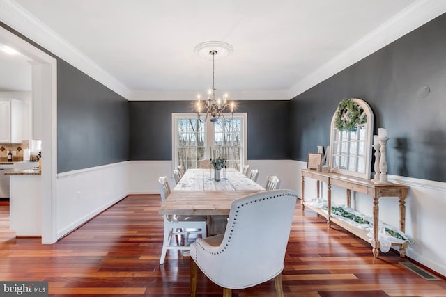 dining area featuring crown molding, dark wood-type flooring, and an inviting chandelier