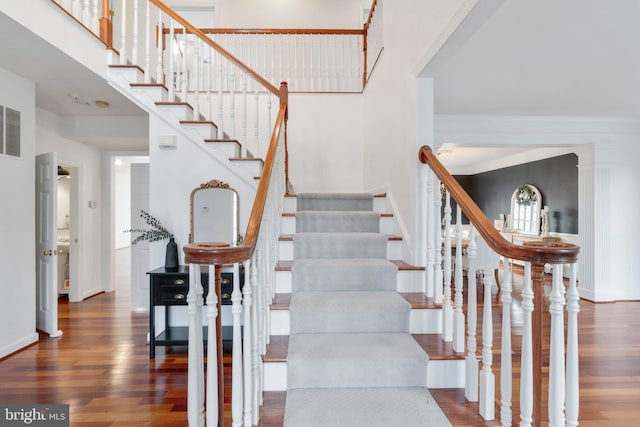 staircase with hardwood / wood-style floors and ornamental molding