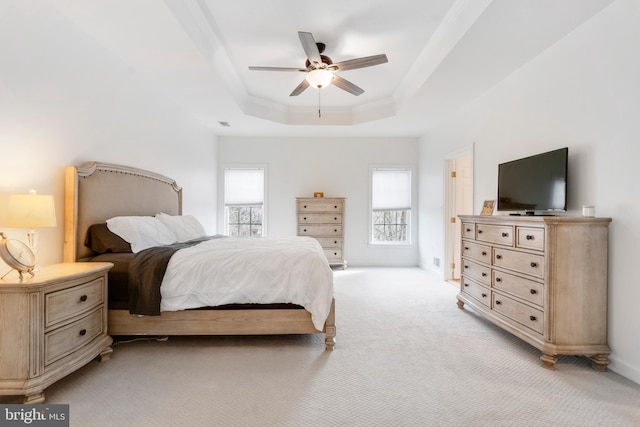 bedroom with a raised ceiling, ceiling fan, and light colored carpet