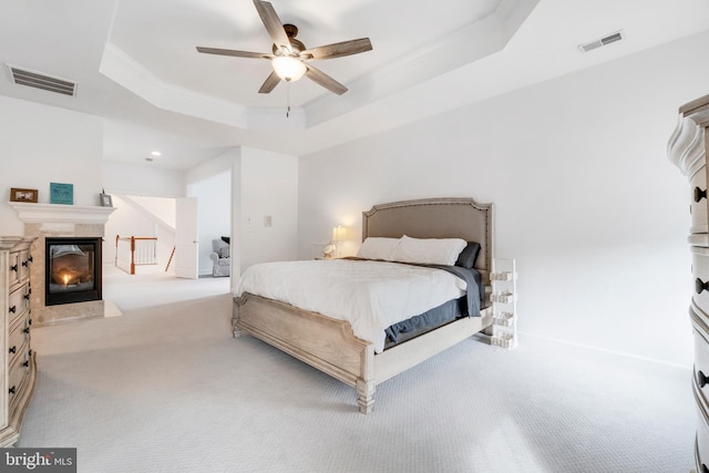 carpeted bedroom with ceiling fan, a raised ceiling, and crown molding