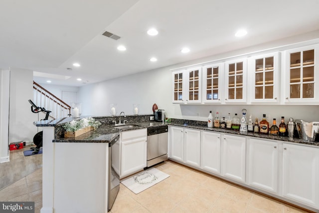 kitchen with white cabinets, kitchen peninsula, stainless steel dishwasher, and dark stone counters