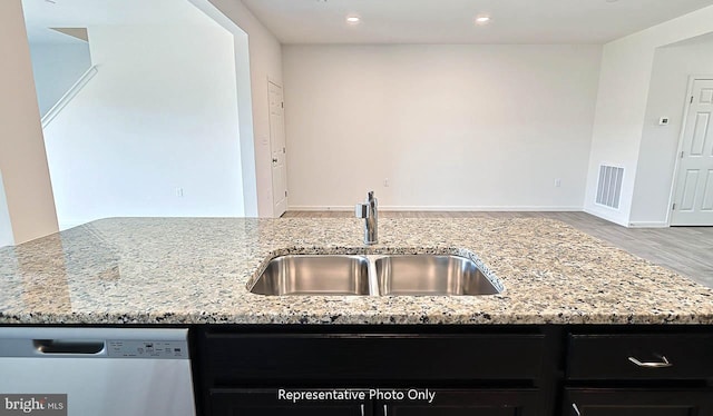 kitchen featuring light stone countertops, stainless steel dishwasher, and sink