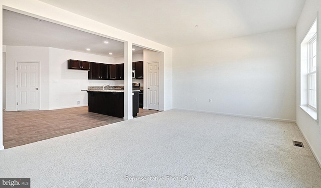 kitchen featuring a breakfast bar, a healthy amount of sunlight, light wood-type flooring, and a kitchen island with sink