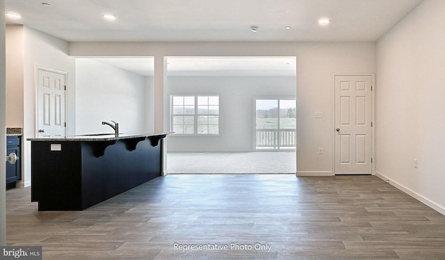 kitchen featuring a kitchen breakfast bar, sink, and light wood-type flooring