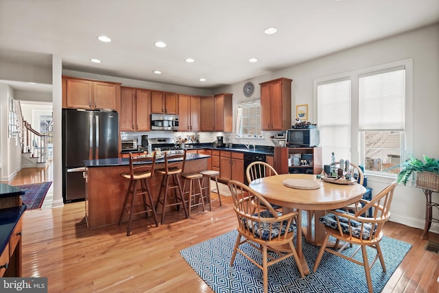 kitchen with a kitchen breakfast bar, light wood-type flooring, stainless steel appliances, sink, and a kitchen island