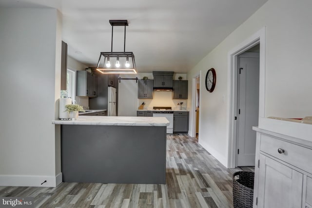 kitchen featuring hardwood / wood-style floors, white appliances, hanging light fixtures, gray cabinets, and kitchen peninsula