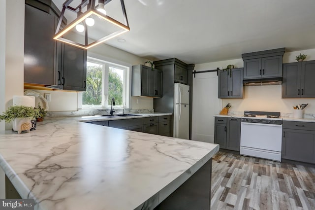 kitchen with gray cabinetry, light hardwood / wood-style floors, white range, and sink