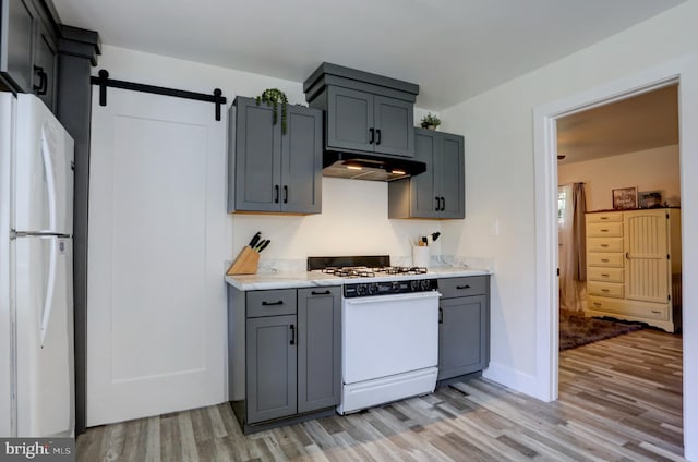 kitchen featuring gray cabinets, a barn door, white appliances, and light hardwood / wood-style flooring