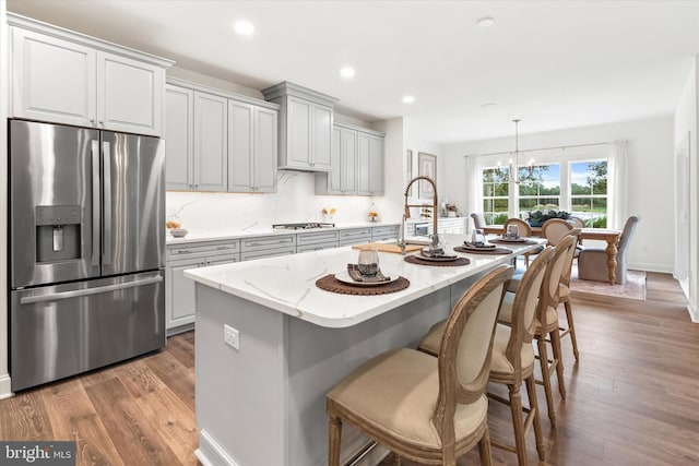 kitchen featuring hardwood / wood-style floors, pendant lighting, stainless steel appliances, and an island with sink