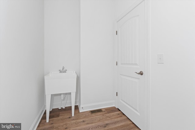 clothes washing area with hardwood / wood-style flooring