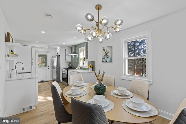 dining room featuring light wood-type flooring, sink, and a chandelier