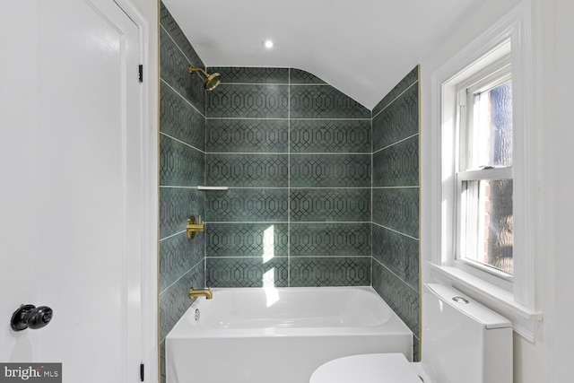 bathroom featuring tiled shower / bath combo, toilet, and lofted ceiling