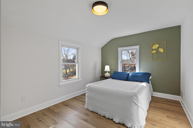 bedroom featuring light wood-type flooring and vaulted ceiling