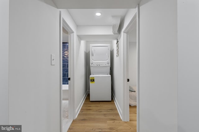 hallway with stacked washer / drying machine and light hardwood / wood-style floors