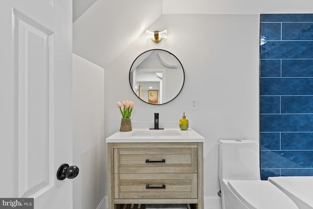 bathroom featuring vanity, toilet, and lofted ceiling