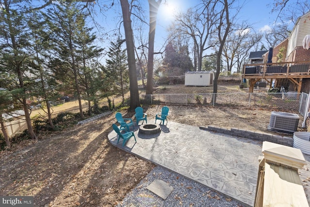 view of yard featuring a deck, central AC, an outdoor fire pit, a patio area, and a storage unit