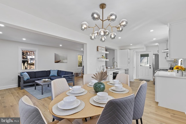 dining area with sink, a notable chandelier, and light wood-type flooring