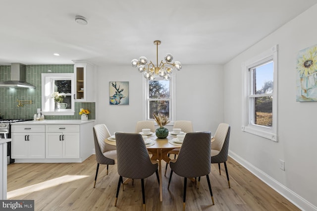 dining area with light wood-type flooring and an inviting chandelier