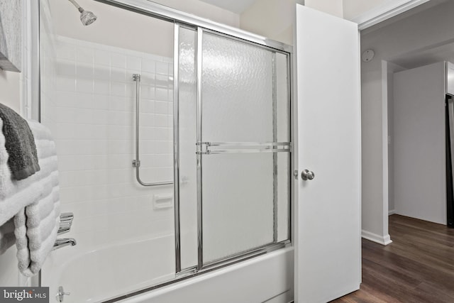 bathroom with hardwood / wood-style floors and bath / shower combo with glass door